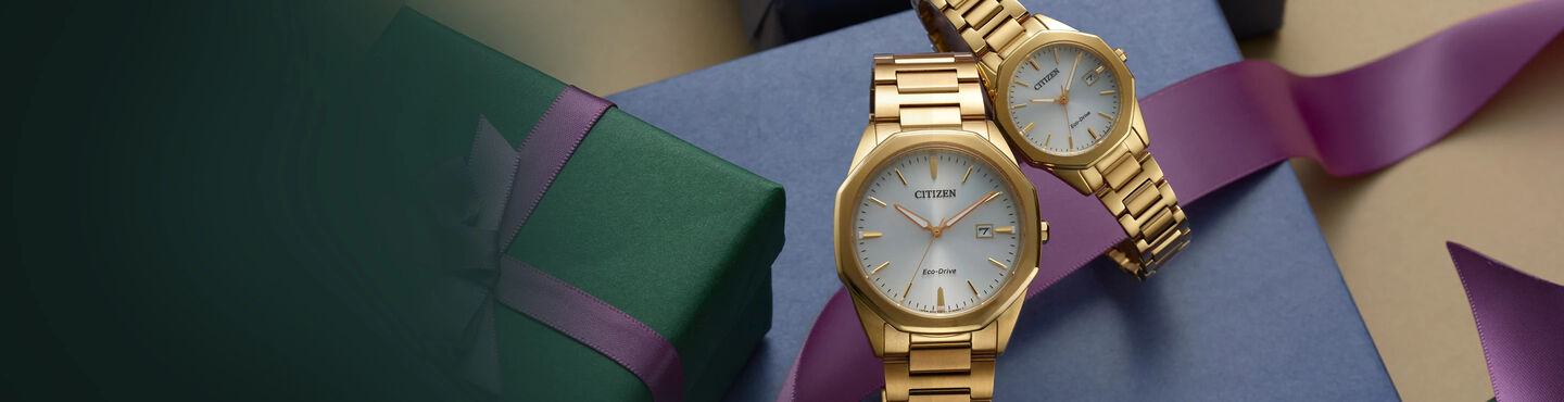 Gift Guide; Men's and women's Corso watch models BM7492-57A and EW2582-59A sitting on top of gift packages
